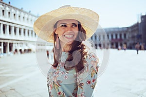 smiling trendy woman in floral dress exploring attractions photo