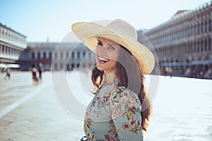 Smiling trendy woman in floral dress with hat