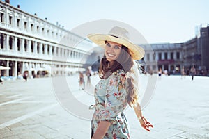 Smiling trendy woman in floral dress with hat having excursion