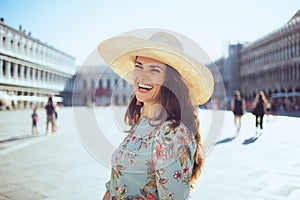 Smiling trendy woman in floral dress having excursion photo