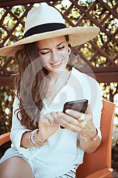 Smiling trendy woman in shirt using smartphone applications