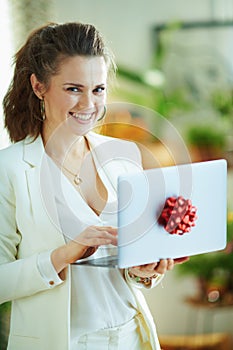 Smiling trendy woman using gift laptop with red bow
