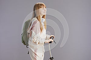 smiling trendy young woman in beige tracksuit with backpack