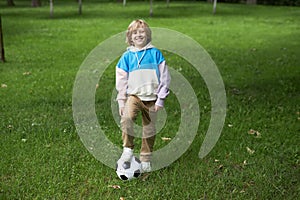 Smiling tween boy with football ball outdoors standing on green grass