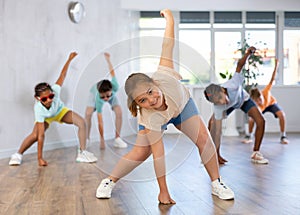 Smiling tween girl dancing krump with group of children in dance studio