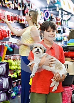 Smiling tweenager boy embracing his puppy during family shopping in pet accessories shop