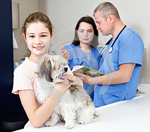 Smiling tweenager girl with her puppy visiting veterinarian clinic