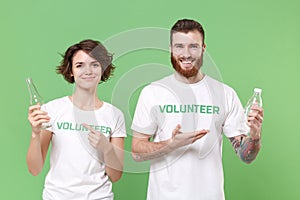 Smiling two friends couple in volunteer t-shirt isolated on pastel green background. Voluntary free work assistance help