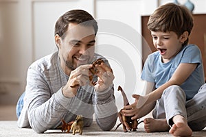 Smiling two generations male family playing with dinosaurs at home.