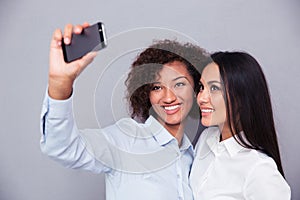 Smiling two girls making selfie photo on smartphone