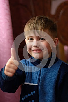 A smiling Ukrainian boy shows a sign ok