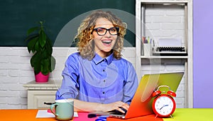 Smiling university student girl preparing for test or exam using laptop. High school. Female teacher in glasses working