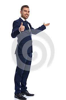 Smiling unshaved guy in elegant suit presenting to side