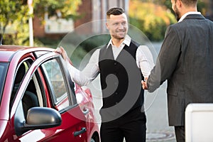 Smiling Valet And Businessperson Standing Near Car