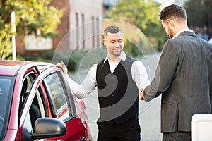 Smiling Valet And Businessperson Standing Near Car
