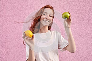 Smiling vegetarian cheerful woman in casual clothes holding apple and orange