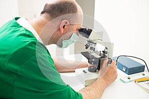 Veterinarian examining under microscope