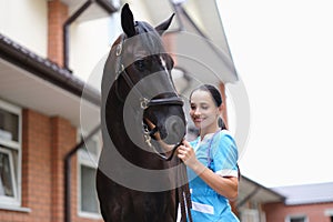 Smiling veterinarian excellently examined a young horse