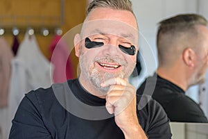 Smiling vivacious man using hydrating gel patches