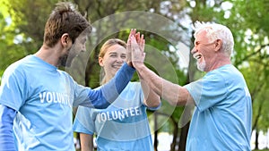 Smiling volunteers giving high five, cooperation gesture, environmental project photo