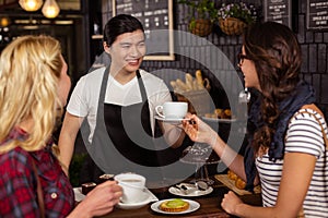 Smiling waiter serving a coffee to a customer