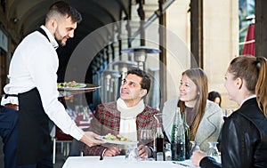 Waiter serving guests at terrace restaurant