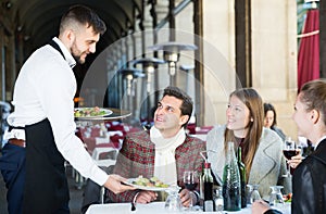 Waiter serving guests at terrace restaurant