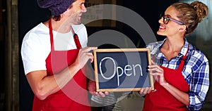 Smiling waiter and waitresses holding open sign board