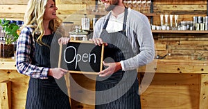 Smiling waiter and waitresses holding open sign board