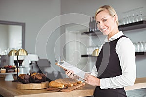 Smiling waitress with clipboard standing at counter