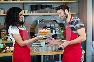 Smiling waitress giving a plate of cake to waiter