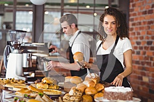 Smiling waitress holding bread roll with tong photo