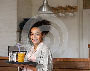 Smiling waitress holding tray of drinks in restaurant