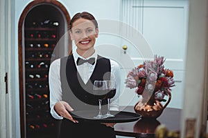 Smiling waitress holding a tray with glasses of red wine