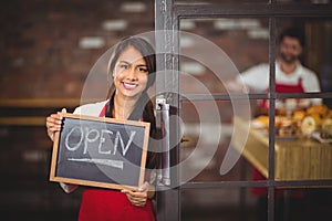 Smiling waitress showing chalkboard with open sign