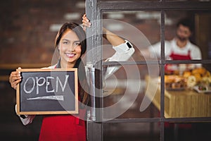 Smiling waitress showing chalkboard with open sign