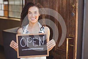 Smiling waitress showing chalkboard with open sign