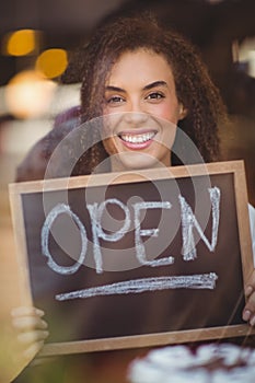 Smiling waitress showing chalkboard with open sign