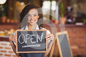 Smiling waitress showing chalkboard with open sign