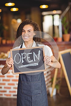 Smiling waitress showing chalkboard with open sign