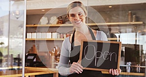 Smiling waitress showing slate with open sign