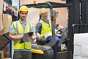 Smiling warehouse worker and forklift driver