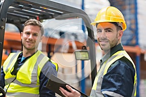 Smiling warehouse worker and forklift driver