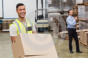 Smiling warehouse worker moving boxes on trolley