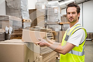Smiling warehouse worker taking a box