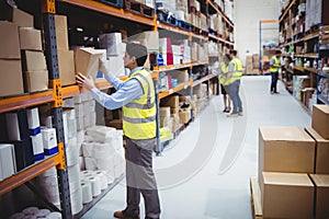 Smiling warehouse worker taking package in the shelf