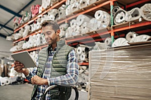 Smiling warehouse worker tracing stock using a digital tablet