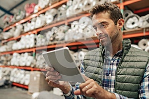 Smiling warehouse worker using a digital tablet to trace stock
