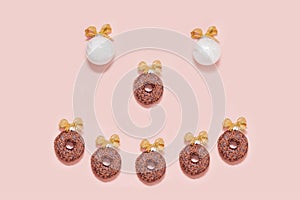 smiling white christmas balls wiht sweet donuts emoticon. new year creative decoration on pink background