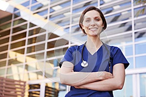 Smiling white female healthcare worker outdoors, waist up